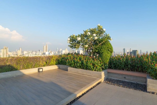flat, open garden rooftop space on a high-rise building with a sprawling city skyline in the distance.