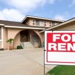 A bright red "For Rent" sign posted outside of a single-story, single-family home with a minimalist vibe.