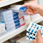 A pharmacist working in the drugstore, grabbing a variety of medications and drugs off the shelf with one item in their hand.