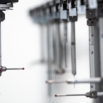 A close-up view of the ends of an automatic 3D measuring system machine. The machine ends are small red orbs.