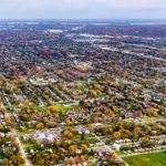 An aerial view of a large expanse of residential neighborhoods in Detroit, Michigan with yellow and green trees.