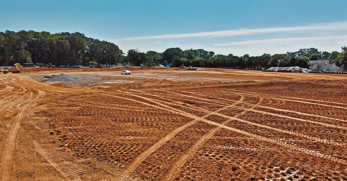 A large plot of cleared land with many different tire tracks crisscrossing the dirt and a tree line in the background.
