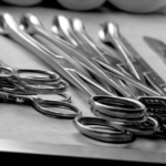 A close-up of surgical scissors and clamps arranged on a sterile tray with metal instruments aligned neatly.