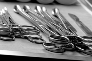 A close-up of surgical scissors and clamps arranged on a sterile tray with metal instruments aligned neatly.