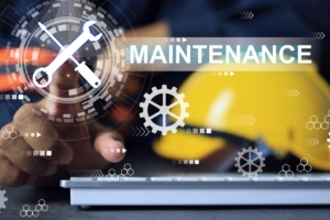 A close-up of a worker's hand pointing to a graphic that reads "Maintenance" with a screwdriver and wrench.