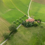 An aerial view of a home that's sitting on the corner of a few country back roads. It is surrounded by farmland.