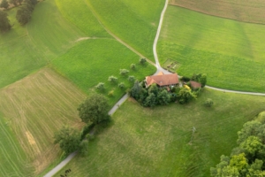 An aerial view of a home that's sitting on the corner of a few country back roads. It is surrounded by farmland.